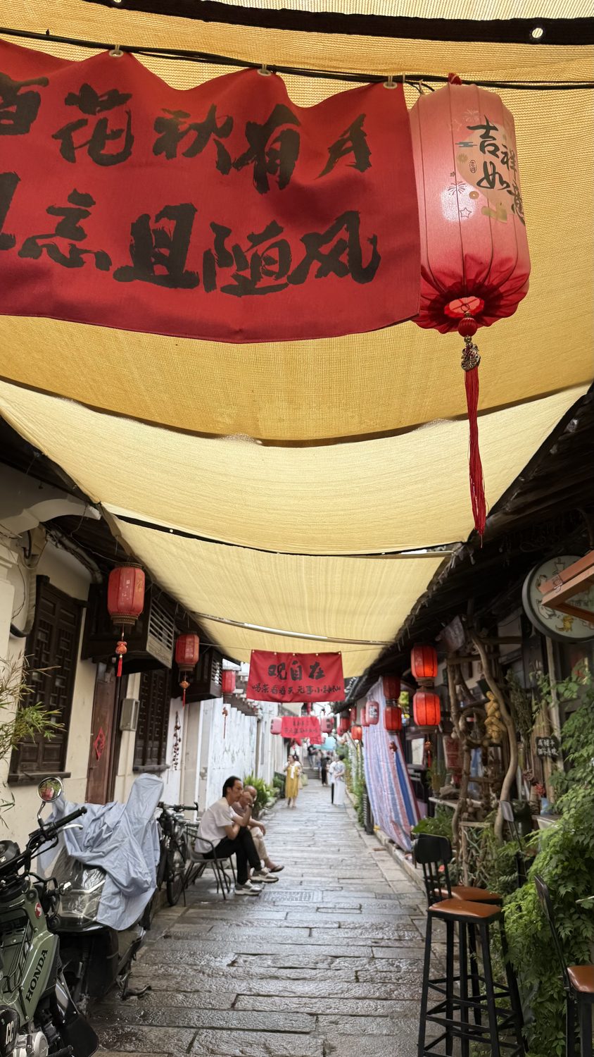 A flagstone lane under awnings and red lanterns in the old quarter
